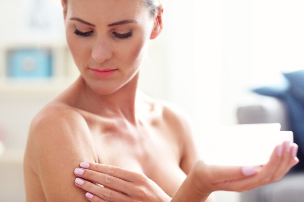 fit woman holding lotion over her body