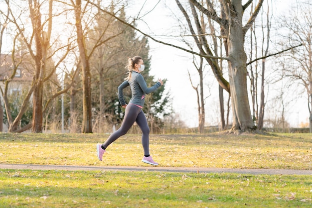 Fit woman running during health crisis with face mask