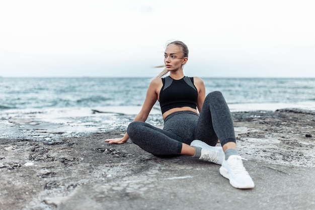 Photo fit woman in sportswear sitting on urban beach