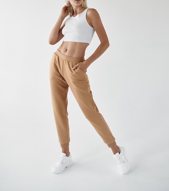 Fit woman standing in light beige pants and white shirt