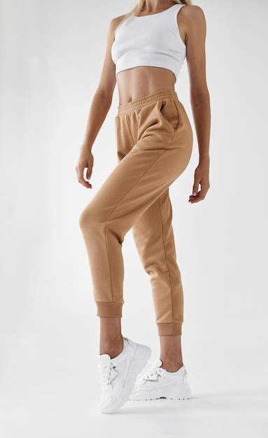 Fit woman standing in light beige pants and white shirt