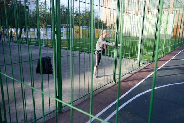 Fit woman stretching her leg on a sports ground