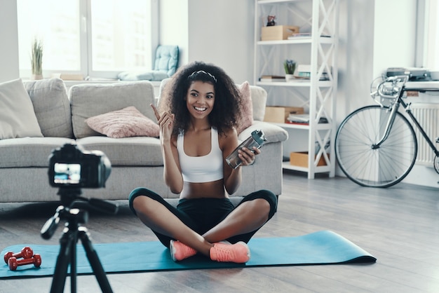 Fit young African woman working out and smiling while making social media video