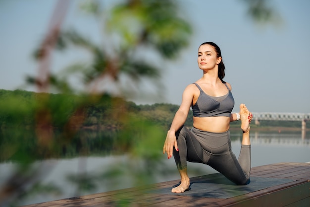 Fit young woman doing yoga outdoors in a beautiful spot on a riverside