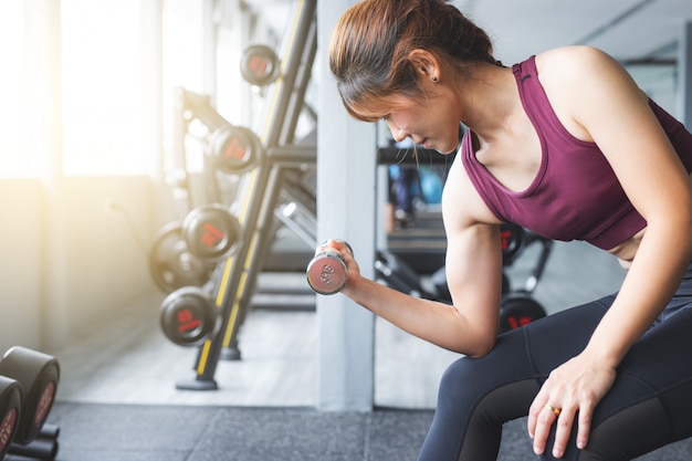 Fitness Asian girl lifting dumbbell at gym.