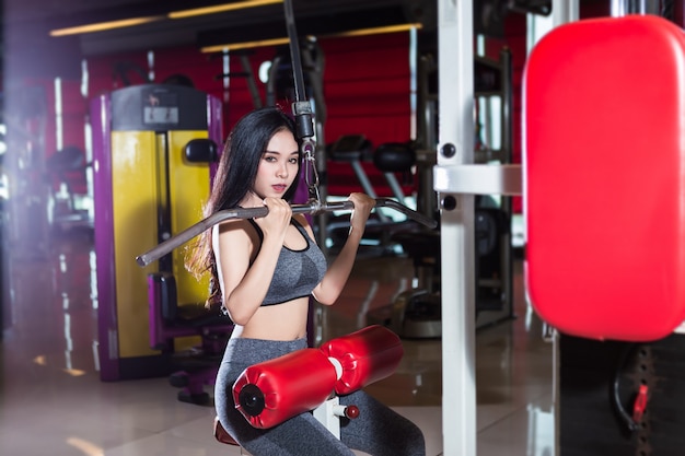 Fitness Asian women performing doing exercises training the shoulder and chest muscles in sport gym interior and health club.