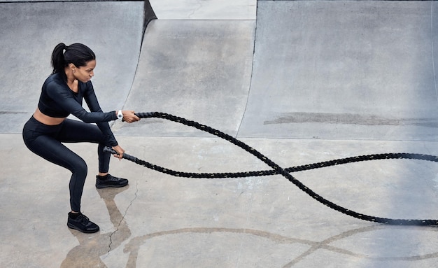 Fitness battle ropes and strong with a black woman athlete outdoor for a workout from above Exercise energy and power with a female training outside using a heavy rope for cardio or endurance