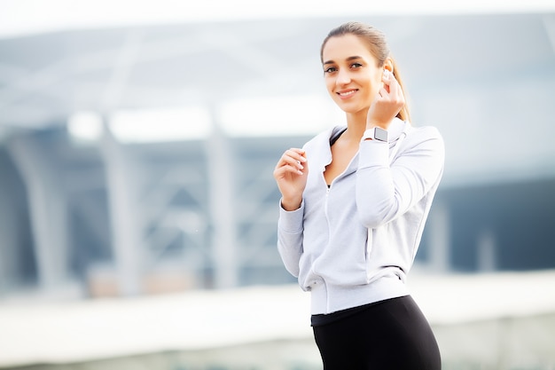 Fitness Beautiful woman drinking water and listen to music after running