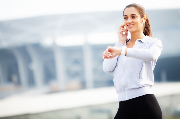 Fitness Beautiful woman drinking water and listen to music after running