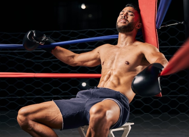 Fitness boxer and man tired in ring out corner exhausted from sports boxing match at the gym or arena Active male in fight club fatigue and relaxing from intense fighting sport workout or exercise