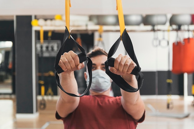 Fitness boy pulls pulleys in the gym