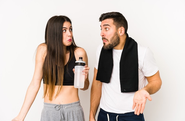 Fitness couple shrugs shoulders in studio