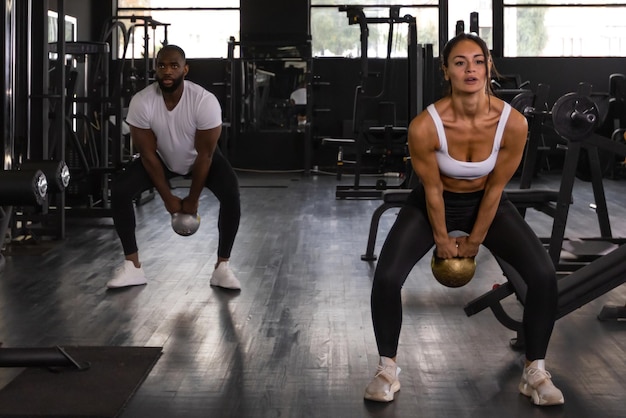 Fitness couple in sportswear doing squat exercises at gym