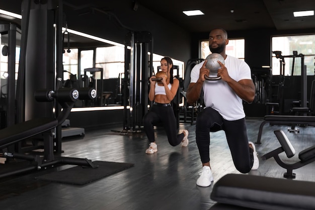 Fitness couple in sportswear doing squat exercises at gym