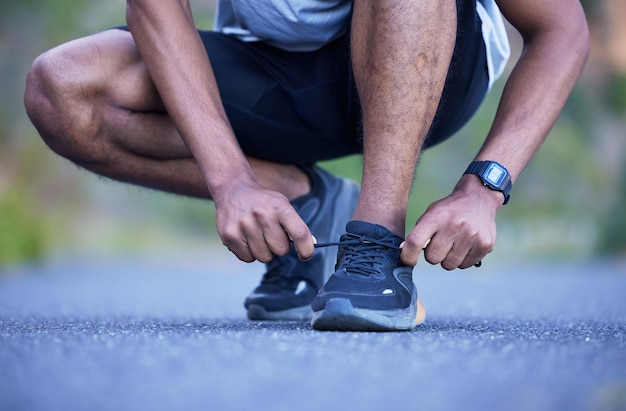 Fitness exercise and a man tying shoelace outdoor for run workout or training performance Closeup of athlete person or runner with running shoes on a road for cardio or health and wellness