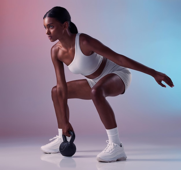 Fitness exercise and woman with a kettlebell in studio strength training and burning calories in a full body exercise Energy workout and healthy girl swings a heavy weight for strong arms and legs