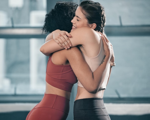 Fitness friends and hug with women in gym for happy exercise and workout Well done congratulations and support with girl athlete training together for sports mindset and wellness motivation