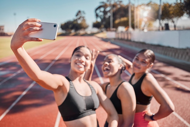 Fitness friends and selfie by runner women group at a running track for training exercise and cardio wellness Sports phone and girl team smile relax and pose for picture after stadium workout