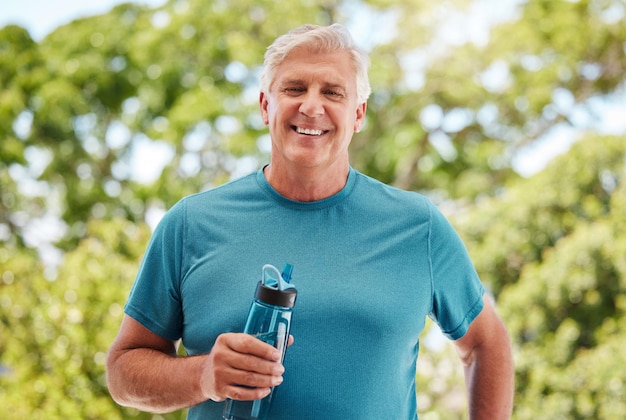 Fitness garden and a senior man with water bottle exercise and hydrate in retirement Health nature and workout a happy elderly guy from Canada with smile standing in outdoor park on a summer day