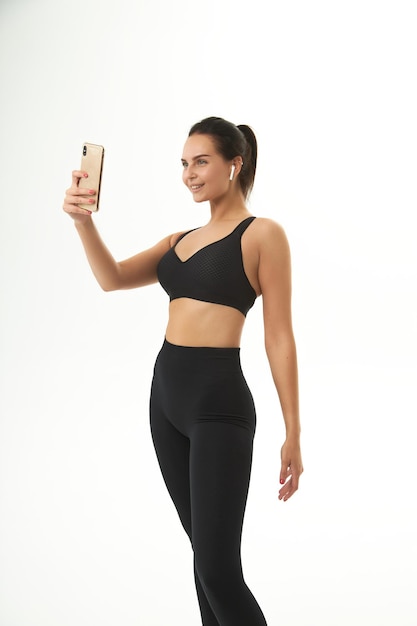 Fitness girl on training in sportswear holds a smart phone in her hands