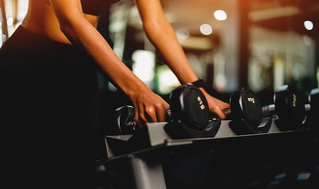 Fitness girl with dumbbells in the gym closeup photo Health and beauty concept of health lovers