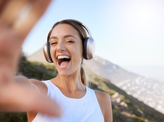 Fitness headphone music and selfie woman enjoying peaceful mountain workout rest for wellbeing Wellness girl happy excited and cheerful photograph break in nature landscape to relax mind