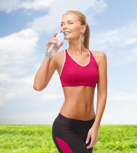 fitness, healthcare and dieting concept - smiling sporty woman with bottle of water