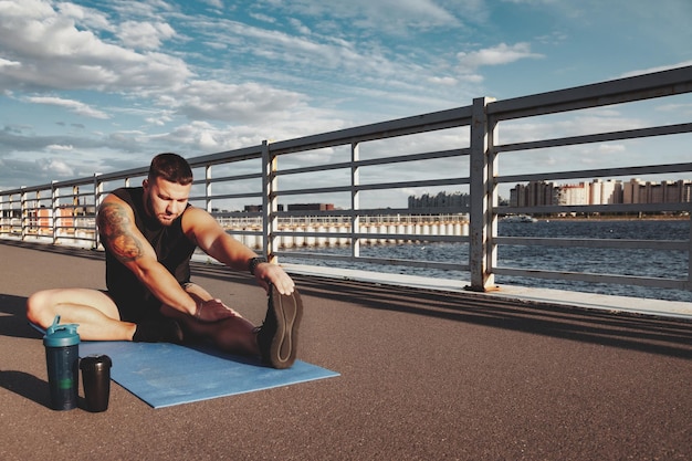 Fitness healthy lifestyle concept with male athlete exercising outdoors in city Muscular handsome bearded man sportsman with cap doing sport exercising