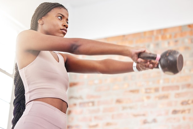 Fitness kettlebell weight and black woman doing a workout with strength motivation and health in a gym Sports focus and African female athlete doing a muscle training exercise in a sport center