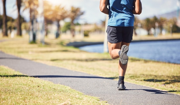 Fitness legs and man or runner outdoor for exercise training or running at a park Closeup and feet of a male athlete in nature for a workout run and cardio performance for health and wellness