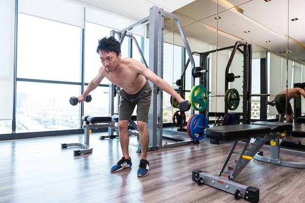 Fitness man are training or exercising by lifting dumbbells. in Fitness room at sport gym.