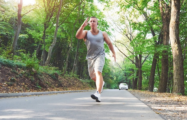 Fitness man athlete jogging in nature during sunset.