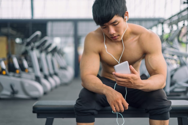 Fitness man relaxing seat listening to music after he exercises