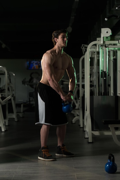 Fitness Man Using Kettlebells Inside Gym