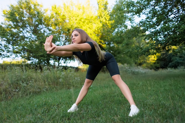 Fitness model goes in for sports in the park outdoors doing forward bends