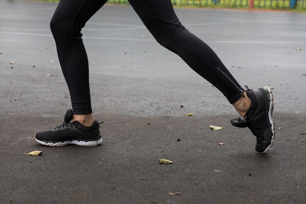 Fitness model in a sports top and leggings stretching before training in the park