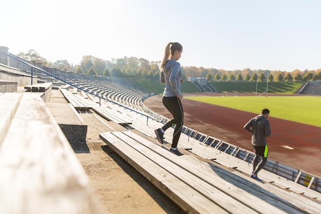 fitness, sport, exercising and lifestyle concept - couple running downstairs on stadium