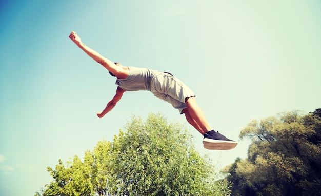 Photo fitness, sport, parkour and people concept - young man jumping in summer park