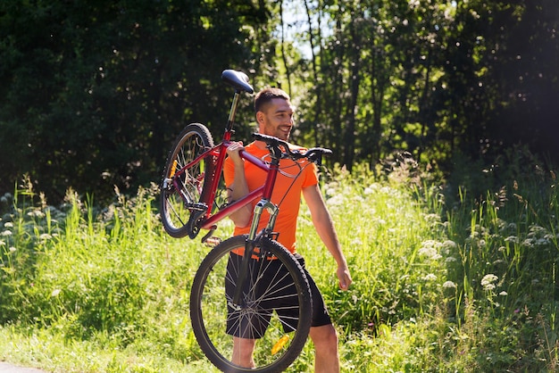 fitness, sport, people and healthy lifestyle concept - happy young man riding bicycle outdoors