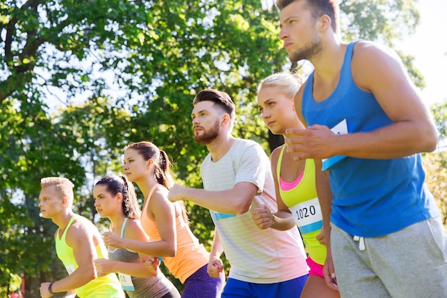 Photo fitness, sport, race and healthy lifestyle concept - group of teenage friends or sportsmen with badge numbers on start of running marathon outdoors