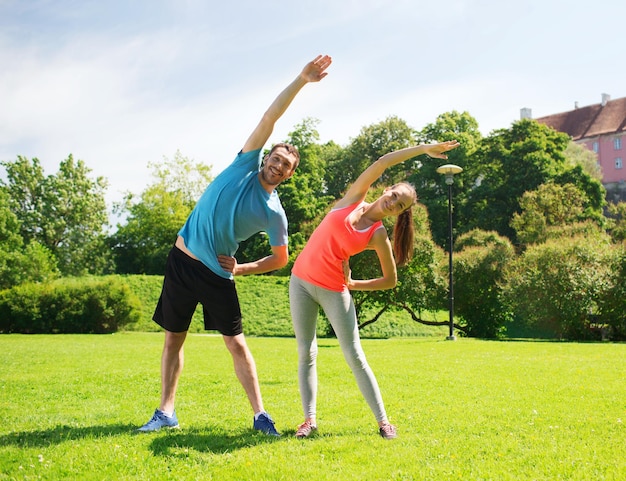 fitness, sport, training and lifestyle concept - smiling couple stretching outdoors