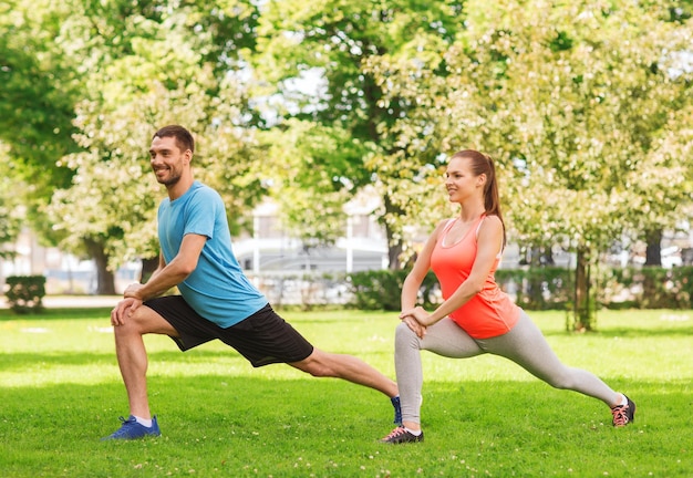 fitness, sport, training and lifestyle concept - smiling couple stretching outdoors