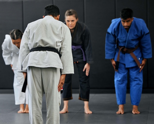 Fitness strength and respect between karate trainer leading a class bow and greeting martial arts student at a dojo or studio Diverse group training and learning self defense and endurance skills