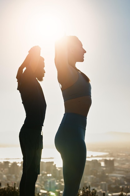 Fitness sunset and couple doing an outdoor exercise or training together on a rooftop in the city Sports healthy and athletes stretching before workout on roof of a building outside in urban town