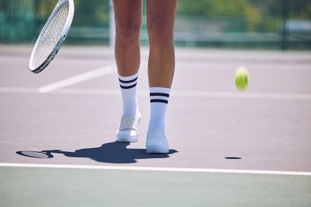 Fitness tennis and sports legs of woman with racket and ball walking on court after serving in training workout or exercise Sporty shoes active or healthy player losing match game or competition