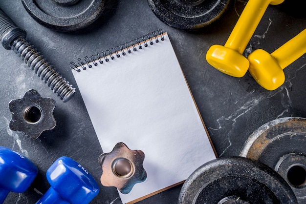 Fitness tools and dumbbells with blank notebook