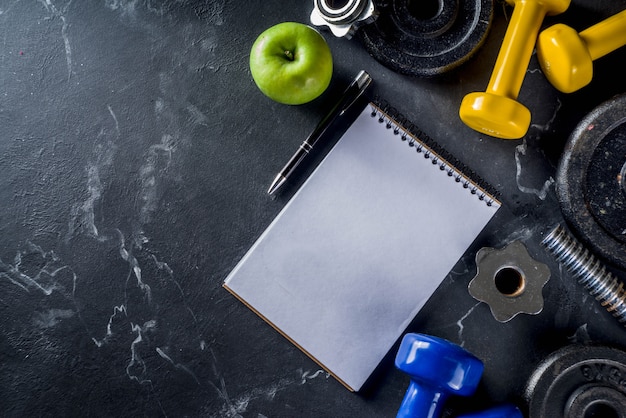 Fitness tools and dumbbells with blank notebook