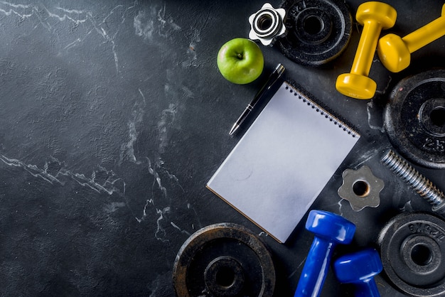 Fitness tools and dumbbells with blank notebook