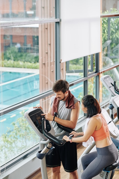 Fitness trainer helping woman to set program