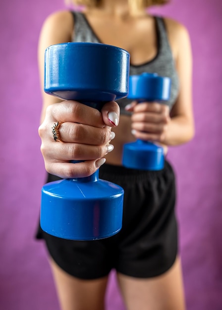 Fitness trainer instructor woman in tracksuit holding dumbbells isolated on plain background